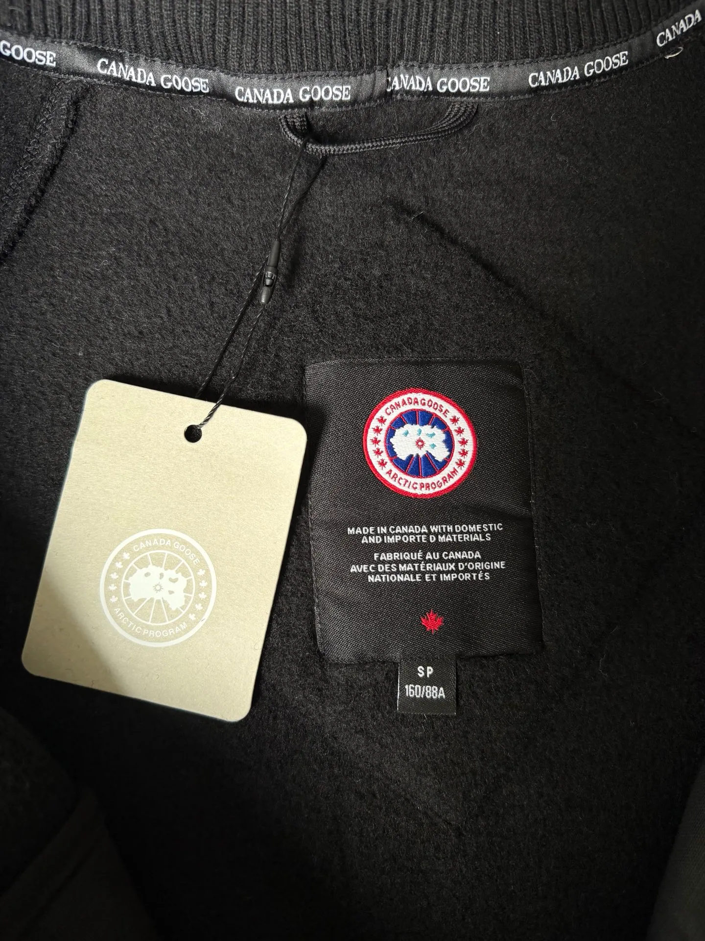 P620 Canada Goose Fleece Wool Baseball Jacket Fabric selection: Wool fleece fabric blended with wool as the main body and a very small amount of spandex and polyester fiber. Wool is a core natural ingredient that provides unparalleled temperature regulation, antibacterial and anti-odor properties and a skin-friendly feel. The feeding of a small amount of spandex gives the fabric a certain degree of four-way elasticity, making it non-restrictive during daily activities. As the basis of fleece's structure, polyester fiber enhances the fabric's durability, wrinkle resistance and quick-drying properties. It contributes to the loft of the fleece and provides functions such as trapping air.  Detail 1: The sleeves and hem are closed with 2×2 ribbing. Its strong elasticity can closely fit wrists and waists of different thicknesses, forming an effective 'seal' to prevent cold wind from blowing back. It can still maintain its original shape after repeated stretching and use, and is not easy to loose and deform. And the ribbed cuffs can convey a sense of design and enhance the visual beauty.  Detail 2: The combination of hood design and elastic buckle improves warmth and windproof performance when wearing. Accessories: Customized elastic drawstring, elastic buckle, custom zipper pendant, custom armband Size: S M L Color: Black Gray Mickey